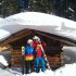 Zwei Skifahrer stehen vor einer tief verschneiten Holzhütte (Skigebiet Hochzeiger)